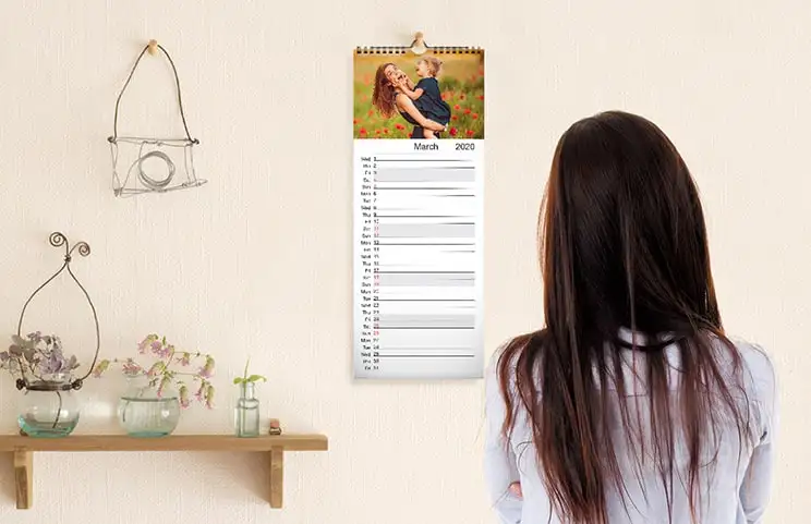 Kitchen calendar hung up on kitchen wall with family holiday photos on