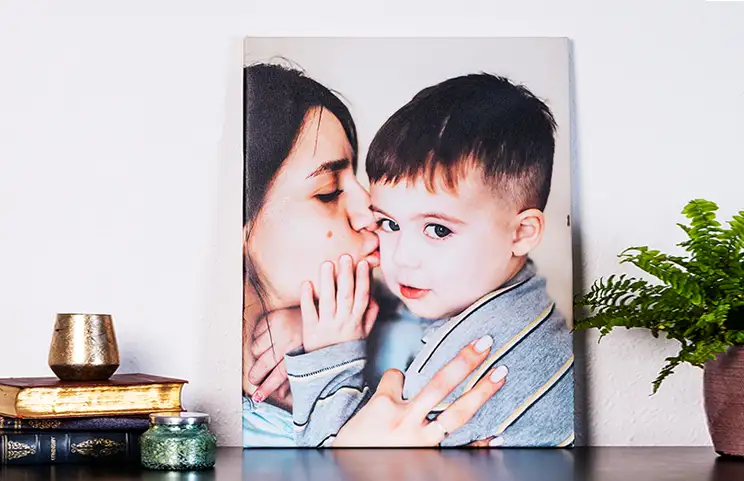 Young woman placing Printerpix custom photo canvas with photo of baby and dog on wall