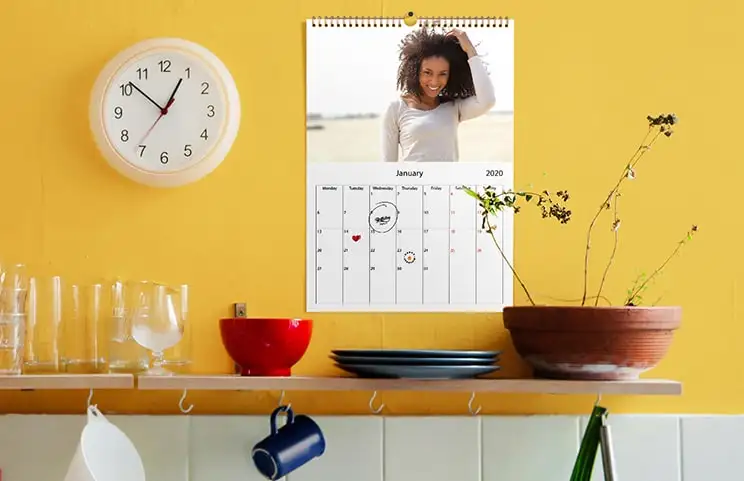 Romantic couple in living room with personalised 2020 wall calendar with proposal photo